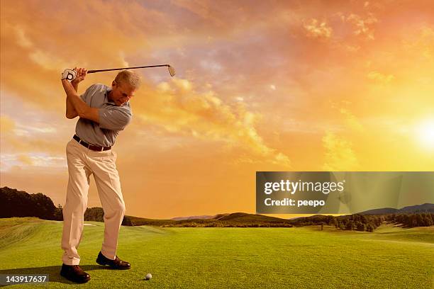 golfer prepares to strike ball at sunset - senior men golf stock pictures, royalty-free photos & images