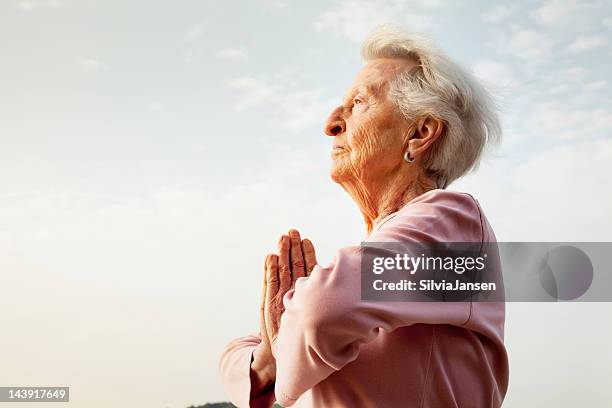 senior frau meditation morgen - eine seniorin allein stock-fotos und bilder