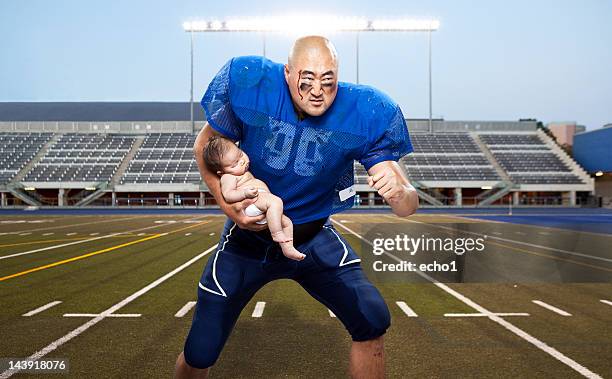 football player protecting baby - football player standing stock pictures, royalty-free photos & images