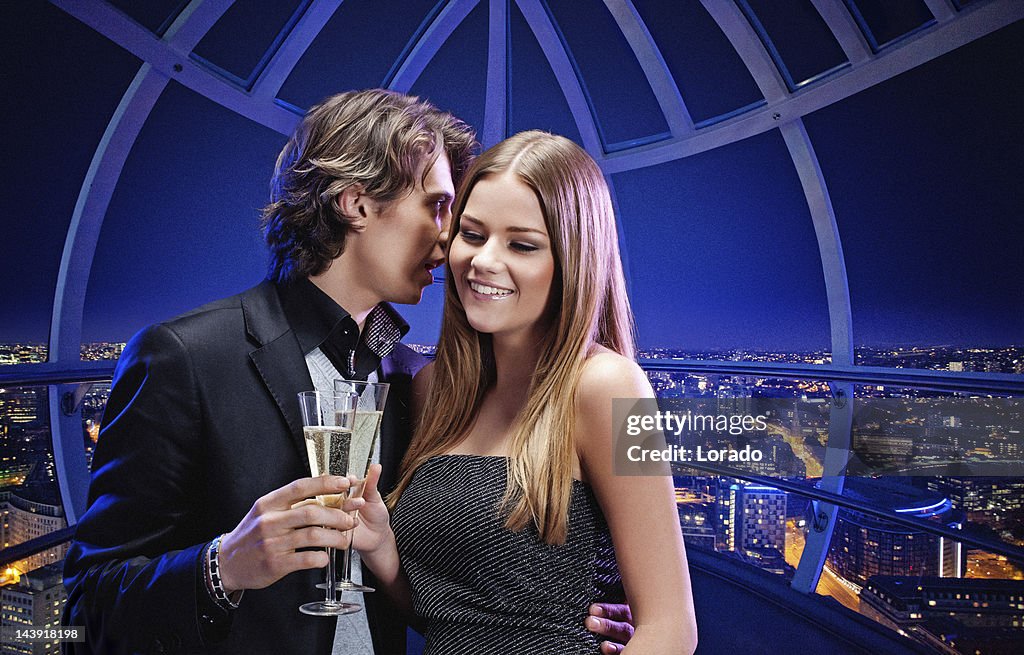 Heureux couple buvant du champagne contre vue aérienne sur la ville