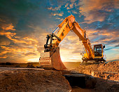 Excavator at a construction site against the setting sun.