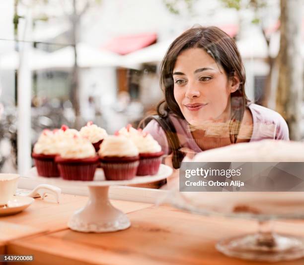 mujer mirando por la ventana de visualización de pastel - hambre fotografías e imágenes de stock