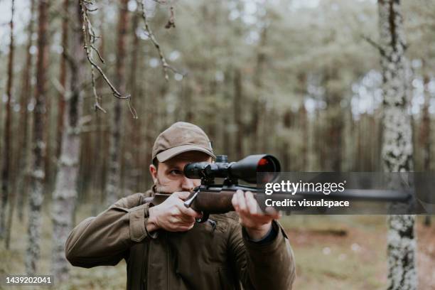 jäger zielt mit jagdgewehr in den herbstwald - hunting stock-fotos und bilder