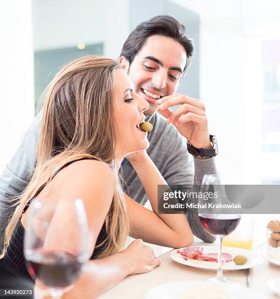 casal jovem tendo diversão no restaurante comer azeitonas, beber vinho. - appetizers imagens e fotografias de stock