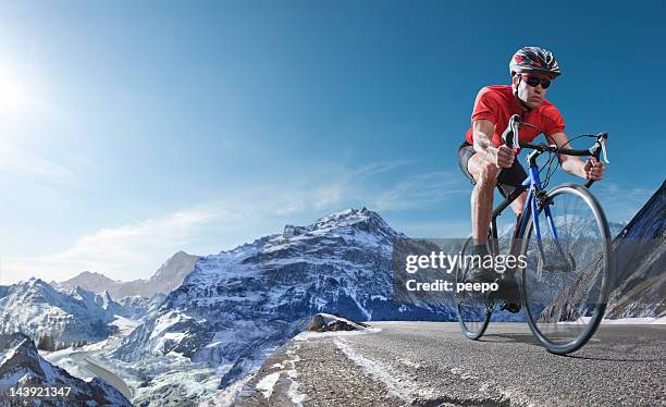 athlete on racing bike cycling through alpine mountains - extreme sports bike stock pictures, royalty-free photos & images