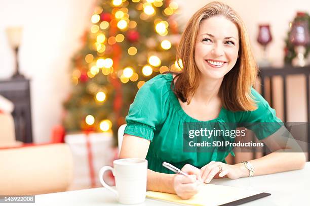 happy woman at christmas writing a letter - christmas list stock pictures, royalty-free photos & images