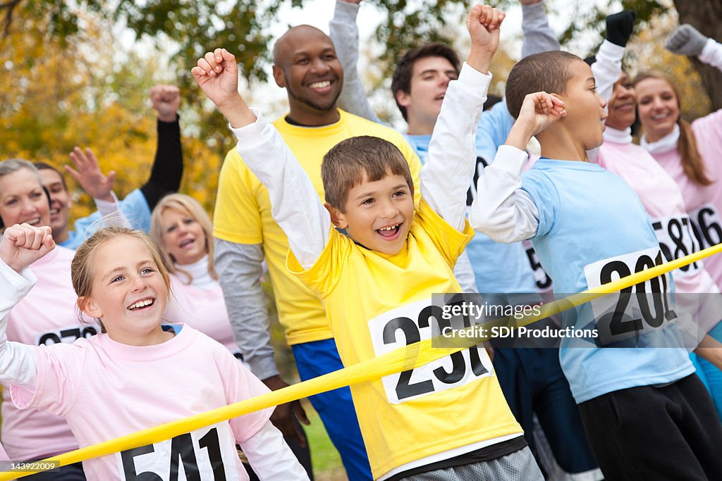 Felizes crianças e adultos feliz cruzar a linha de chegada na corrida