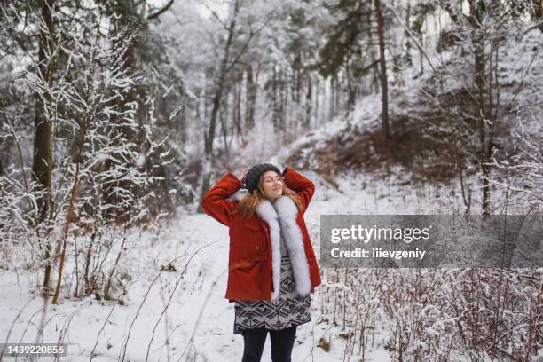 redhead woman in red jacket with fur and hat in winter forest. pretty woman enjoying vacation. girl in nature. feel happiness. hoarfrost and snow on trees - belarus nature stock pictures, royalty-free photos & images