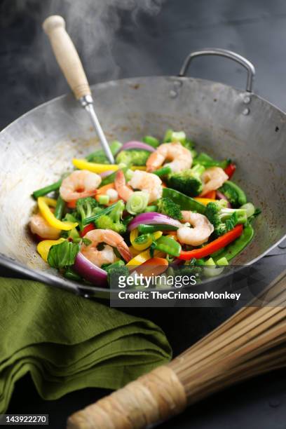 a steaming wok filled with shrimp stir fry with vegetables - stirfry stock pictures, royalty-free photos & images