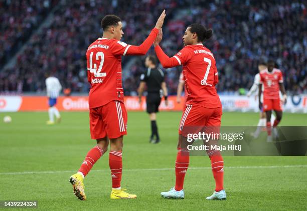 Jamal Musiala of Bayern Munich celebrates with teammate Serge Gnabry after scoring their team's first goal during the Bundesliga match between Hertha...