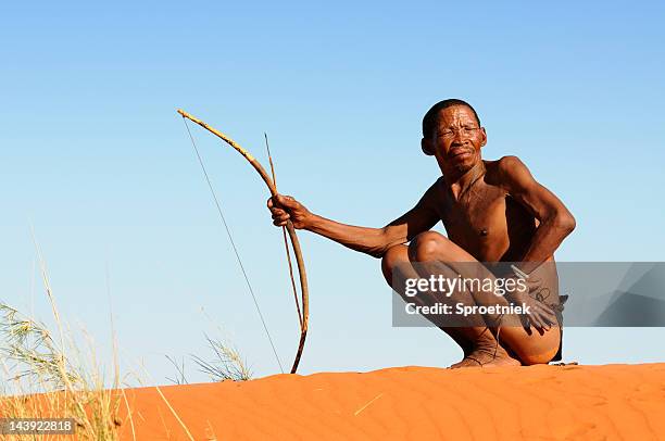 lone kalahari bushman on red sand dune - kalahari desert stockfoto's en -beelden