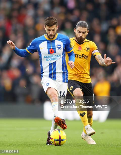 Adam Lallana of Brighton & Hove Albion is challenged by Ruben Neves of Wolverhampton Wanderers during the Premier League match between Wolverhampton...