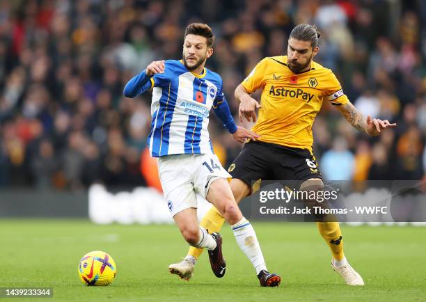 Adam Lallana of Brighton & Hove Albion is challenged by Ruben Neves of Wolverhampton Wanderers during the Premier League match between Wolverhampton...