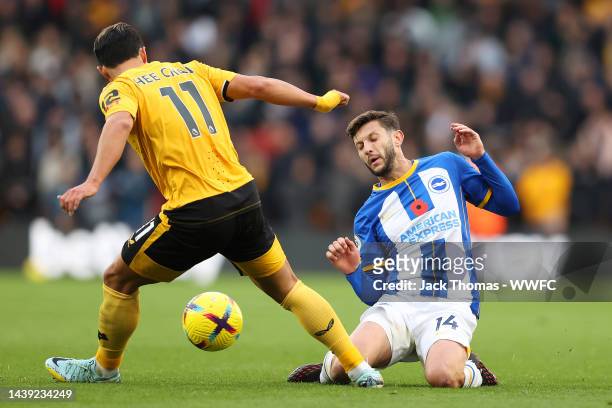 Adam Lallana of Brighton & Hove Albion is challenged by Hwang Hee-chan of Wolverhampton Wanderers during the Premier League match between...