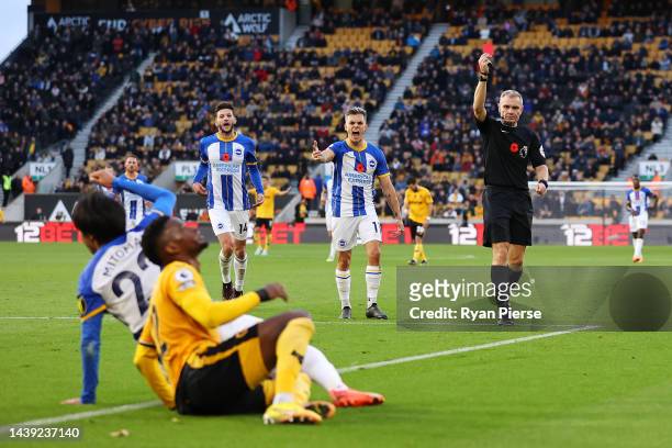 Referee Graham Scott shows the red card to Nelson Semedo of Wolverhampton Wanderers after tackling Kaoru Mitoma of Brighton & Hove Albion during the...