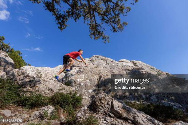 clambering a rock - a man running uphill - escalada libre fotografías e imágenes de stock