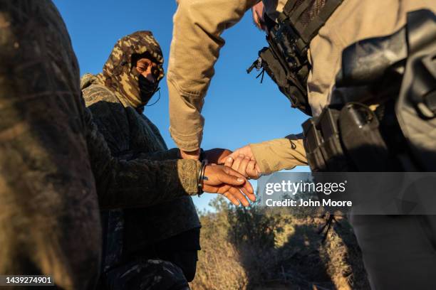 Customs and Border Protection agent removes handcuffs from a camouflaged Mexican migrant detained near the U.S.-Mexico border on November 04, 2022...