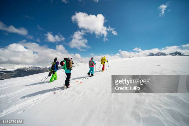 group of people going off piste in mountains - skiing and snowboarding stockfoto's en -beelden
