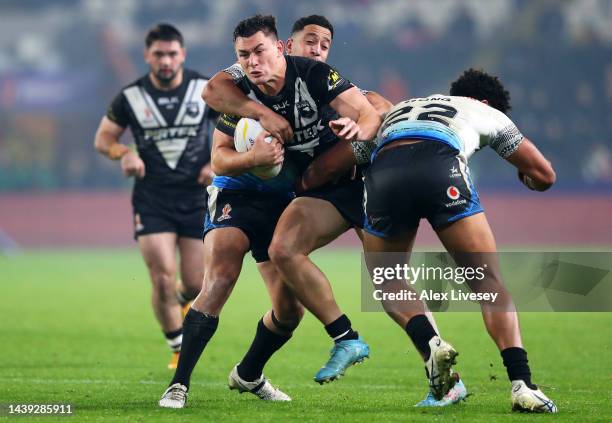 Joseph Manu of New Zealand is tackled by Brandon Wakeham and Siua Wong of Fiji during the Rugby League World Cup Quarter Final match between New...