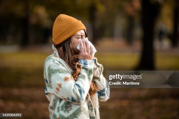 mujer con pañuelo en otoño estornudos - sonarse fotografías e imágenes de stock