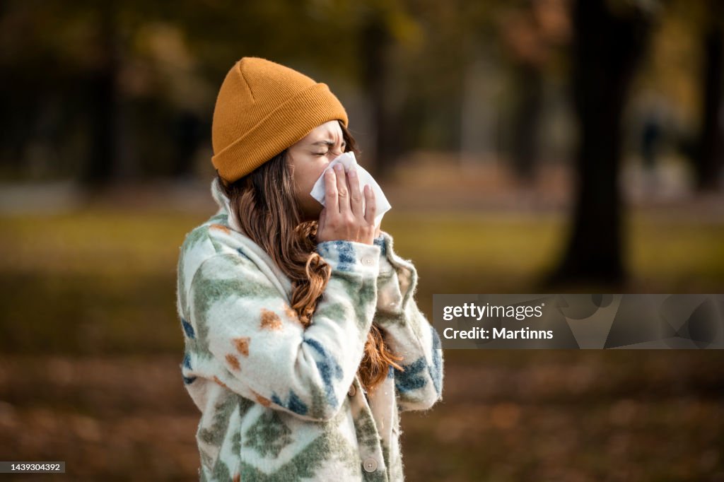 Woman sneezing in handkerchief at autumn