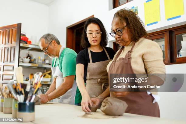 middle-aged people in a pottery class - earthenware stock pictures, royalty-free photos & images