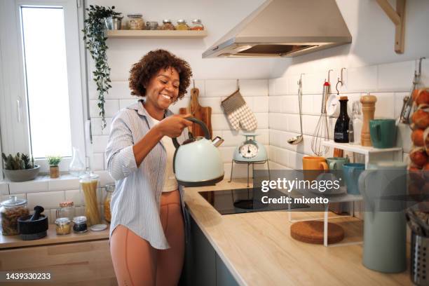 woman with a kettle in the kitchen - kettle stock pictures, royalty-free photos & images