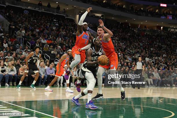 Jrue Holiday of the Milwaukee Bucks is defended by Mike Muscala and Luguentz Dort of the Oklahoma City Thunder during the first half of a game at...