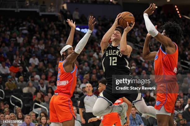 Grayson Allen of the Milwaukee Bucks is defended by Shai Gilgeous-Alexander and Jalen Williams of the Oklahoma City Thunder during the first half of...