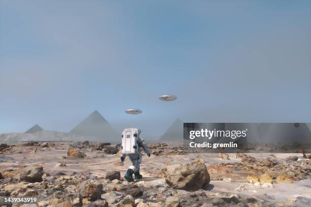 astronaut walking towards mysterious pyramid on distant planet - civilization stockfoto's en -beelden