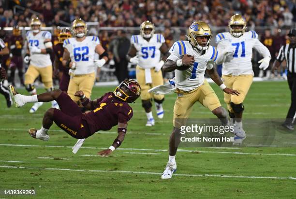 Dorian Thompson-Robinson of the UCLA Bruins runs with the ball while breaking a tackle by Jordan Clark of the Arizona State Sun Devils during the...