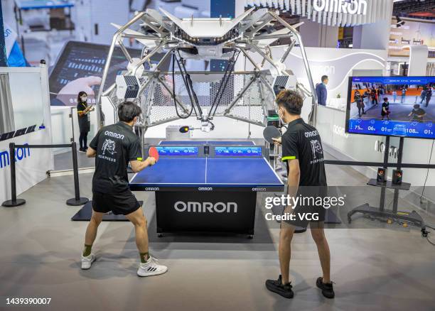 Staff members play table tennis with a robot at Omron booth during the 5th China International Import Expo at the National Exhibition and Convention...