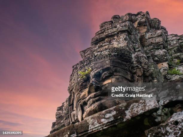 siem reap cambodia temple faces - ancient civilisation of the khmer city complex face sculpture with over grown jungle, trees and nature. top tourist attraction, travel, tourism and adventure concept. - angkor wat bayon stockfoto's en -beelden