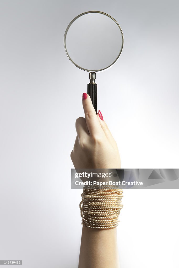 Hand holding up a magnifying glass