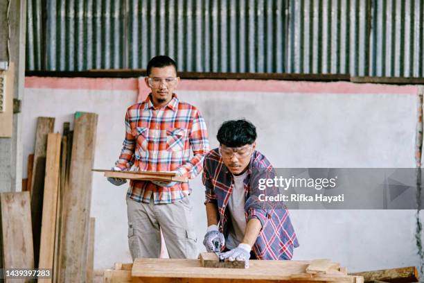 young adult asian carpenter wokring using measure tape in workshop. - wokring out stock pictures, royalty-free photos & images