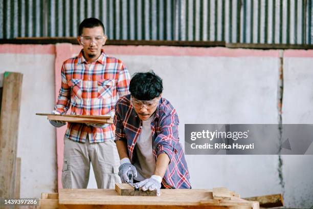 young adult asian carpenter wokring using measure tape in workshop. - wokring out stock pictures, royalty-free photos & images