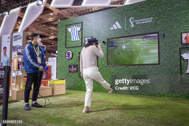 Visitor wearing VR headset plays a football game at Adidas game during the 5th China International Import Expo at the National Exhibition and...