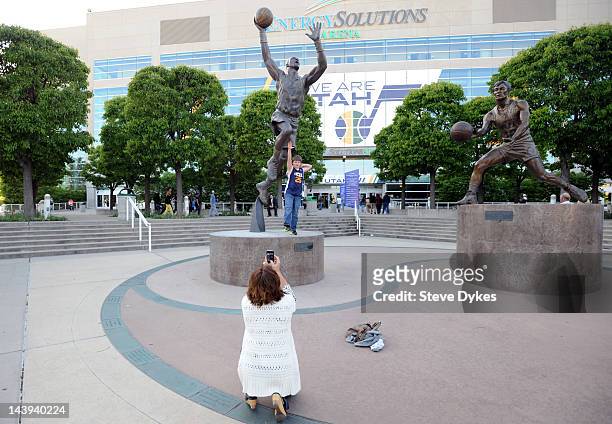 Fans pose in font of statues of Karl Malone and John Stockton before Game Three of the Western Conference Quarterfinals in the 2012 NBA Playoffs at...