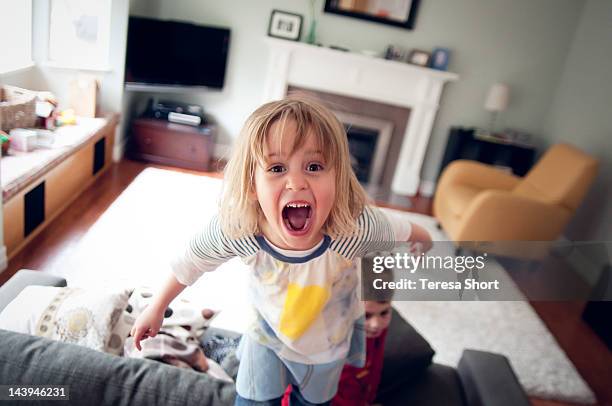 young girl screaming and standing on couch - misbehaviour fotografías e imágenes de stock