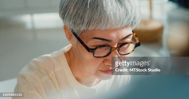 close-up hand asian senior elderly woman, older people, mature lady wear glasses sit on chair use brush create abstract artwork on canvas in workshop at home. - craft show stock pictures, royalty-free photos & images