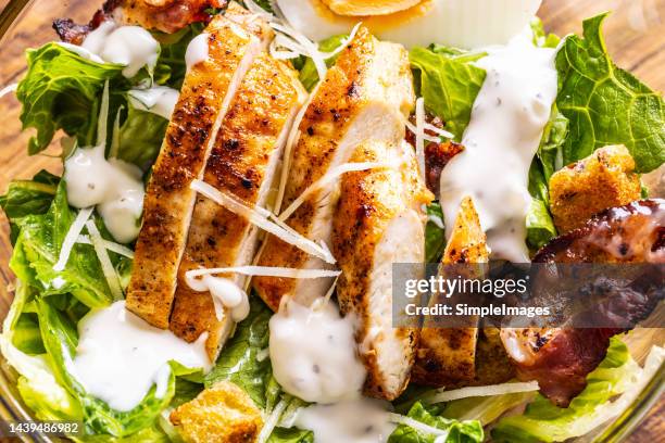 very tasty caesar salad with grilled chicken, garlic dressing, baked bacon and croutons - close up. - croûton photos et images de collection