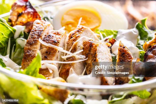 delicious caesar salad with grilled chicken slices in a glass bowl. - pechuga de pollo fotografías e imágenes de stock