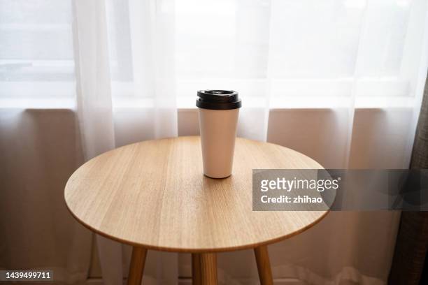 a metal coffee cup on a round table - mesa redonda imagens e fotografias de stock