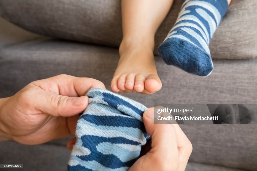 Father putting socks to son