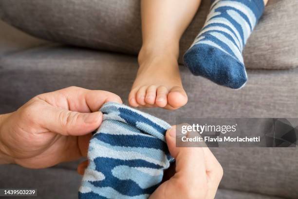 father putting socks to son - babybekleidung stock-fotos und bilder