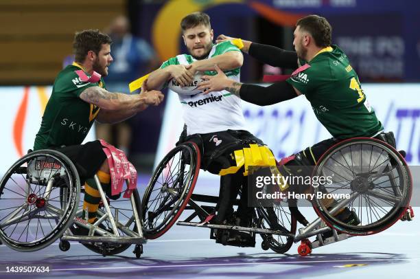 Tom Martin of Ireland is tackled by Diab Karim and Adam Tannock of Australia during the Wheelchair Rugby League World Cup Group A match between...