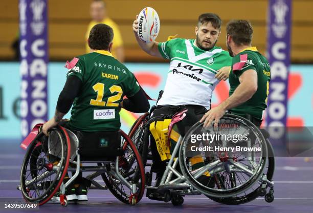 Tom Martin of Ireland is tackled by Diab Karim and Adam Tannock of Australia during the Wheelchair Rugby League World Cup Group A match between...