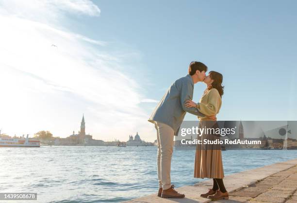 young asian couple by the grand canal of venice in a sunny autumn day - young couple red sunny stockfoto's en -beelden