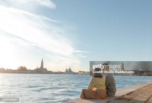 young asian couple by the grand canal of venice in a sunny autumn day - young couple red sunny stockfoto's en -beelden