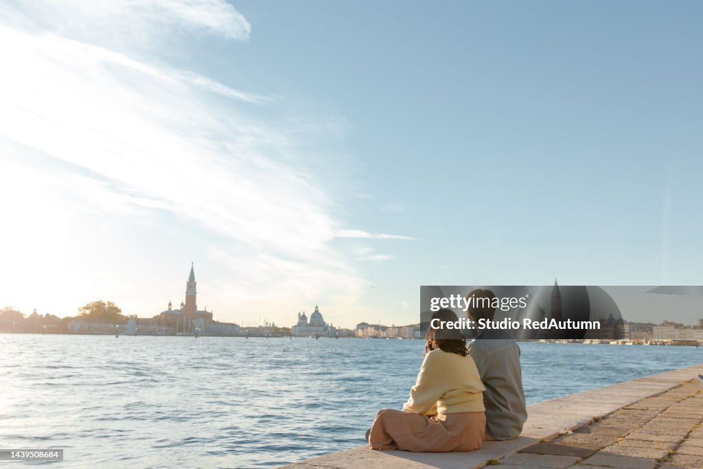 Young asian couple by the grand canal of Venice in a sunny autumn day